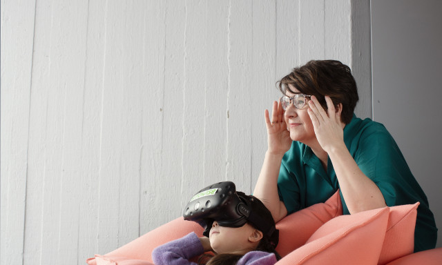 Tyttö katsoo VR-laseilla sohvalla.