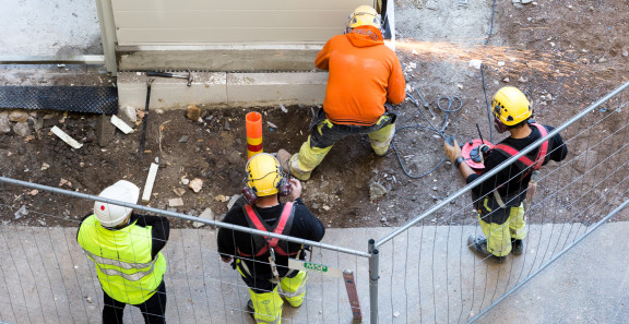 Suunnittelija ja urakoitsijan edustajat rakennuksen pihalla.