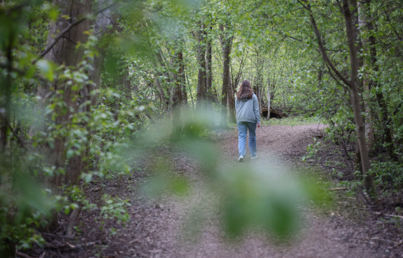Nuori nainen kävelee metsäpolulla.