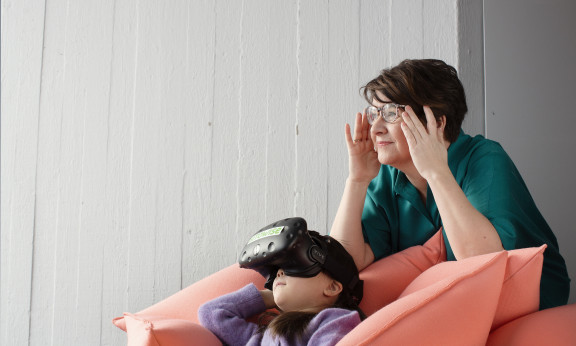 Tyttö katsoo VR-laseilla sohvalla.